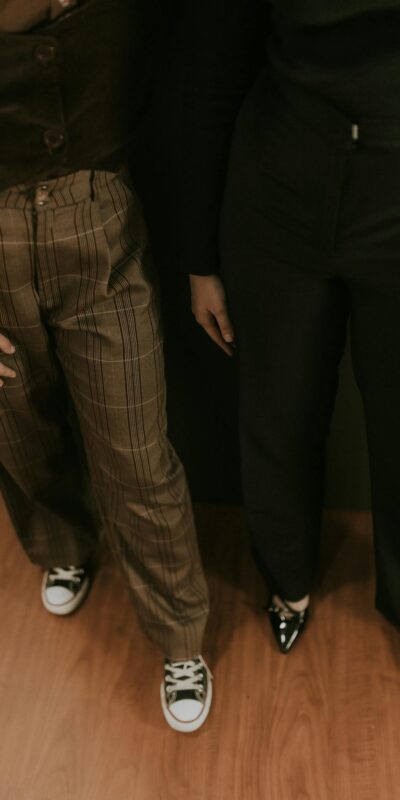 A stylish pair showcasing trendy pants and footwear with a warm indoor ambience.