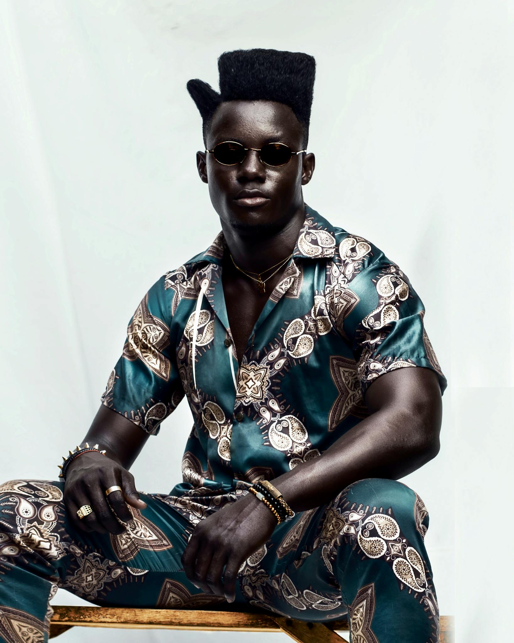Confident man in a vibrant patterned outfit, exuding style and poise.