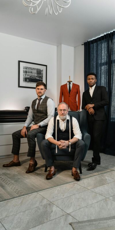 Three well-dressed men in a tailor's atelier showcasing elegance and style in men's fashion.