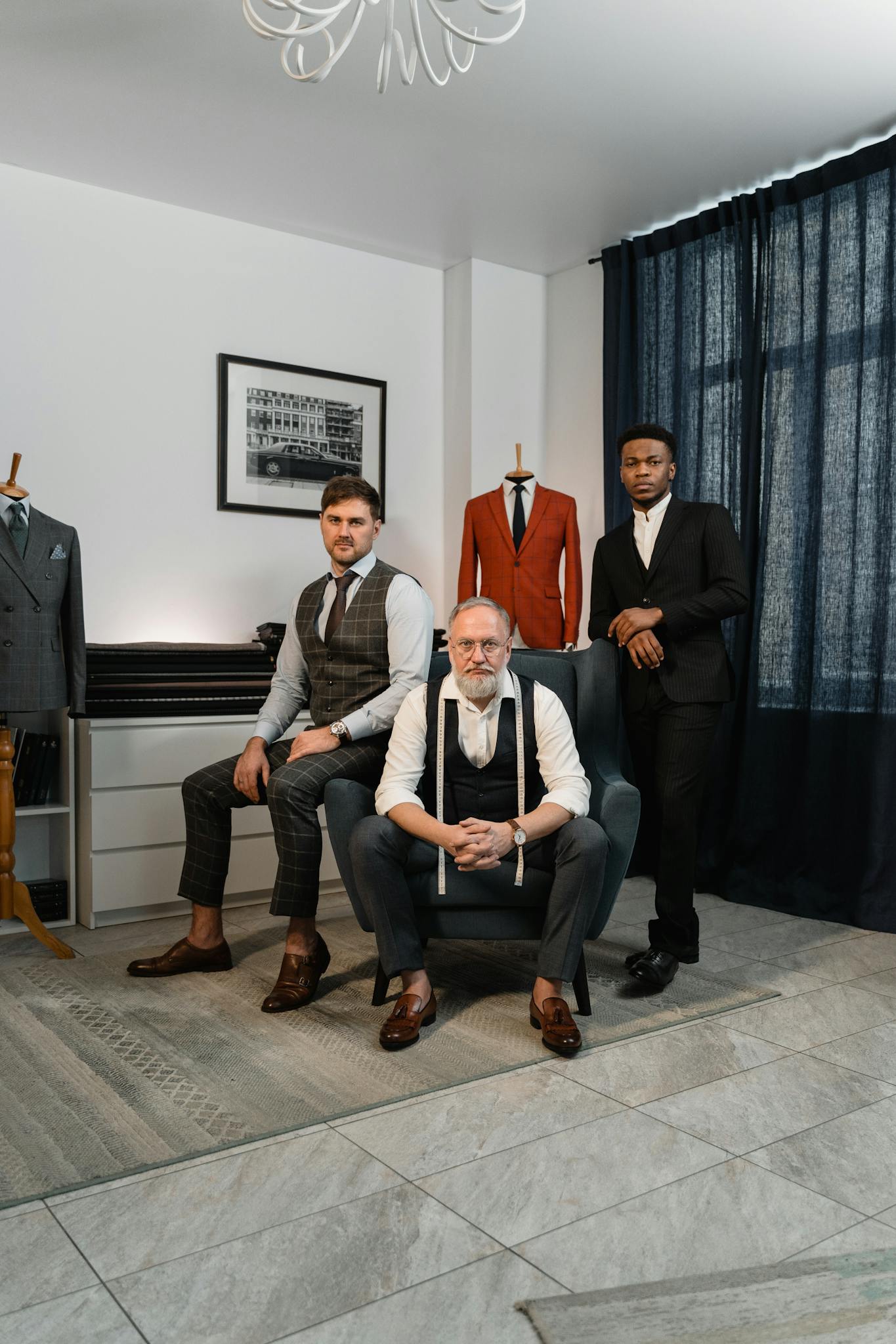 Three well-dressed men in a tailor's atelier showcasing elegance and style in men's fashion.